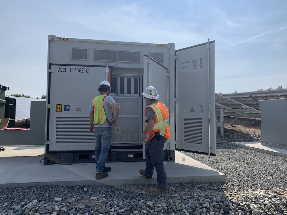 Solar farm workers inspecting power storage