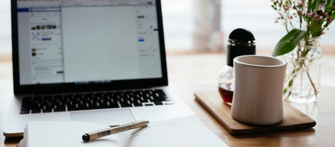 Laptop and a notepad with a pen on a table
