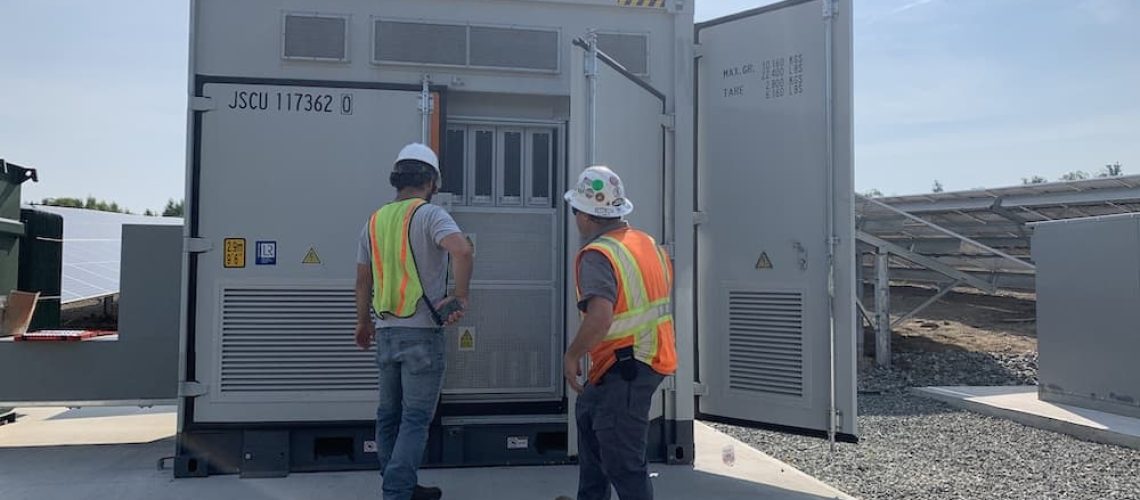 Solar farm workers inspecting power storage